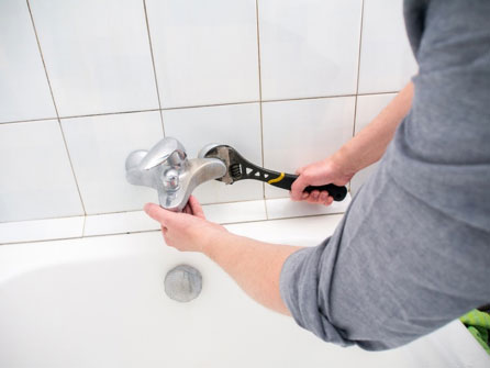 Wichita plumber removing old bathroom faucet in bathtub