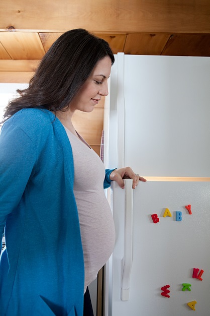 Pregnant woman in front of refrigerator, vulnerable people who need electricity on during a storm